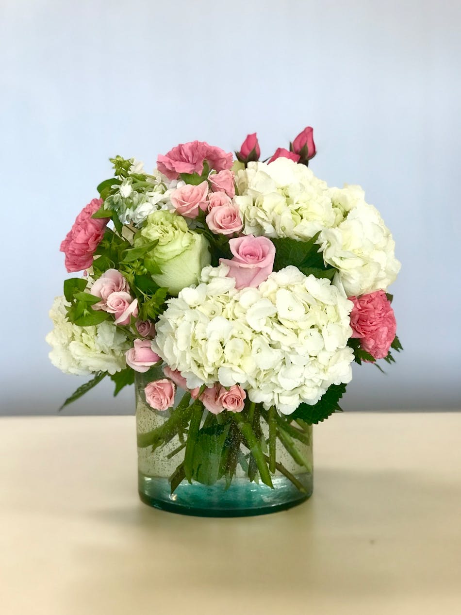 Hydrangea and roses in a clear glass vase.